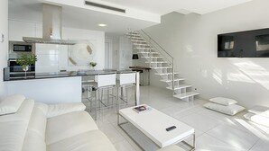 Un espace de vie moderne comprenant une cuisine, un coin repas et un escalier menant à un niveau supérieur.