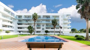 A modern hotel with a swimming pool, multiple balconies, and palm trees. - Charming Family Apartment in Santa Margarita: Pool, Parking, Near Beach and Shops (Roses)