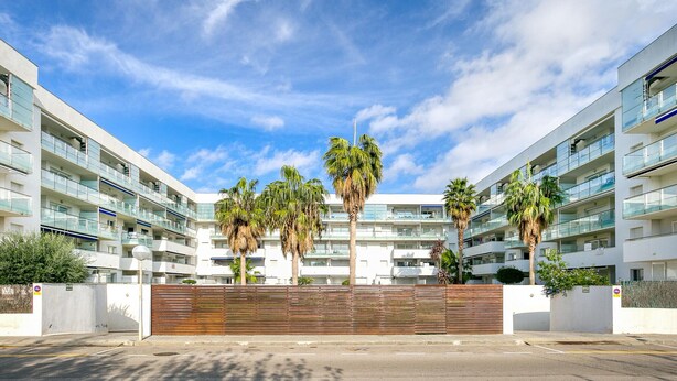 A modern multi-story building with balconies, palm trees, and a clear sky. - Charming Family Apartment in Santa Margarita: Pool, Parking, Near Beach and Shops (Roses)