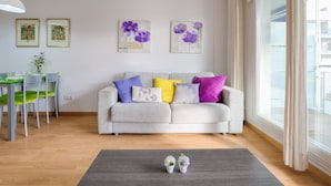 A living room with a grey sofa, a dining table with chairs, and artwork on the walls. - Charming Family Apartment in Santa Margarita: Pool, Parking, Near Beach and Shops (Roses)
