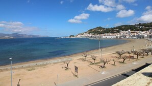 A coastal road with a beach, a clear sky, and a town in the background. - Seafront Penthouse for 6 with Terrace and Shared Pool (El Port de la Selva)