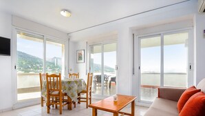 A spacious balcony with a dining area, a sofa, and a TV mounted on the wall. - Seafront Penthouse for 6 with Terrace and Shared Pool (El Port de la Selva)