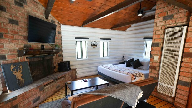 A log cabin interior with a bed, a fireplace, a television, and a window with a view. - Wildlife Lookout Summ (Mount Laguna)