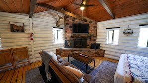 A log cabin interior with a fireplace, wooden furniture, and a mounted deer head. - Wildlife Lookout Summ (Mount Laguna)