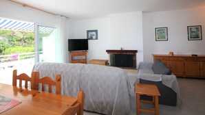 Ein Wohnzimmer mit Esstisch, Stühlen, einer Couch, einem Fernseher und einem Kamin.