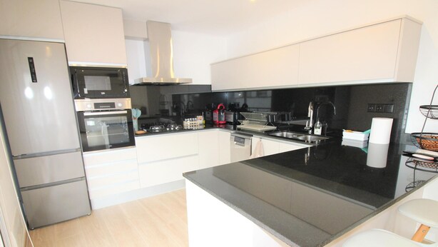 A modern kitchen with stainless steel appliances, a black countertop, and white cabinetry. - Modern Renovated 3BR Apartment, 50m from Beach, Heart of Llançà Port (Llançà)