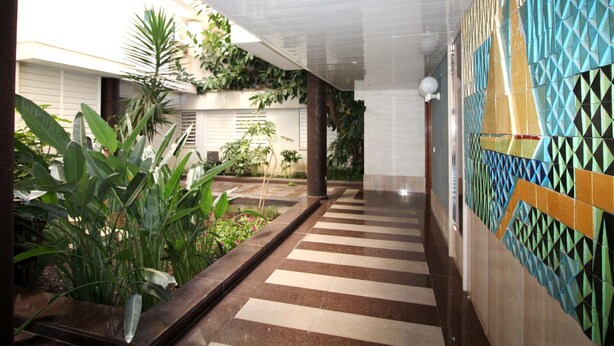 A corridor with patterned walls, a tiled floor, and indoor plants. - Modern seafront apartment with air conditioning in Llançà (Llançà)
