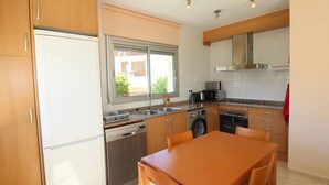 Une cuisine moderne avec des meubles en bois, des appareils électroménagers en acier inoxydable et une fenêtre donnant sur l’extérieur.