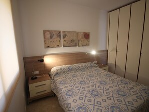 Ein Schlafzimmer mit Bett, Nachttischen, einer Lampe und einem Kleiderschrank.