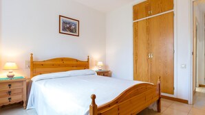 Quarto com cama de madeira, mesas de cabeceira com abajures, guarda-roupa e quadro na parede.