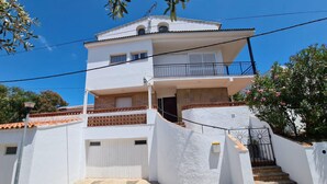 Un immeuble de deux étages, à la façade blanche, doté d’un balcon à l’étage supérieur et d’une entrée fermée par un portail.