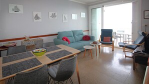 A living room with a sofa, chairs, a dining table, and artwork on the walls. - Apartment with Terrace 300m from Beach, Parking Included (Llançà)