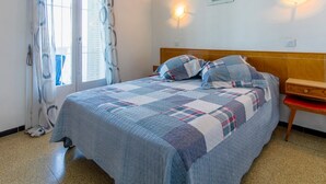 A bedroom with a bed, a nightstand, a window with curtains, and wall-mounted lights. - Apartment with Terrace 300m from Beach, Parking Included (Llançà)