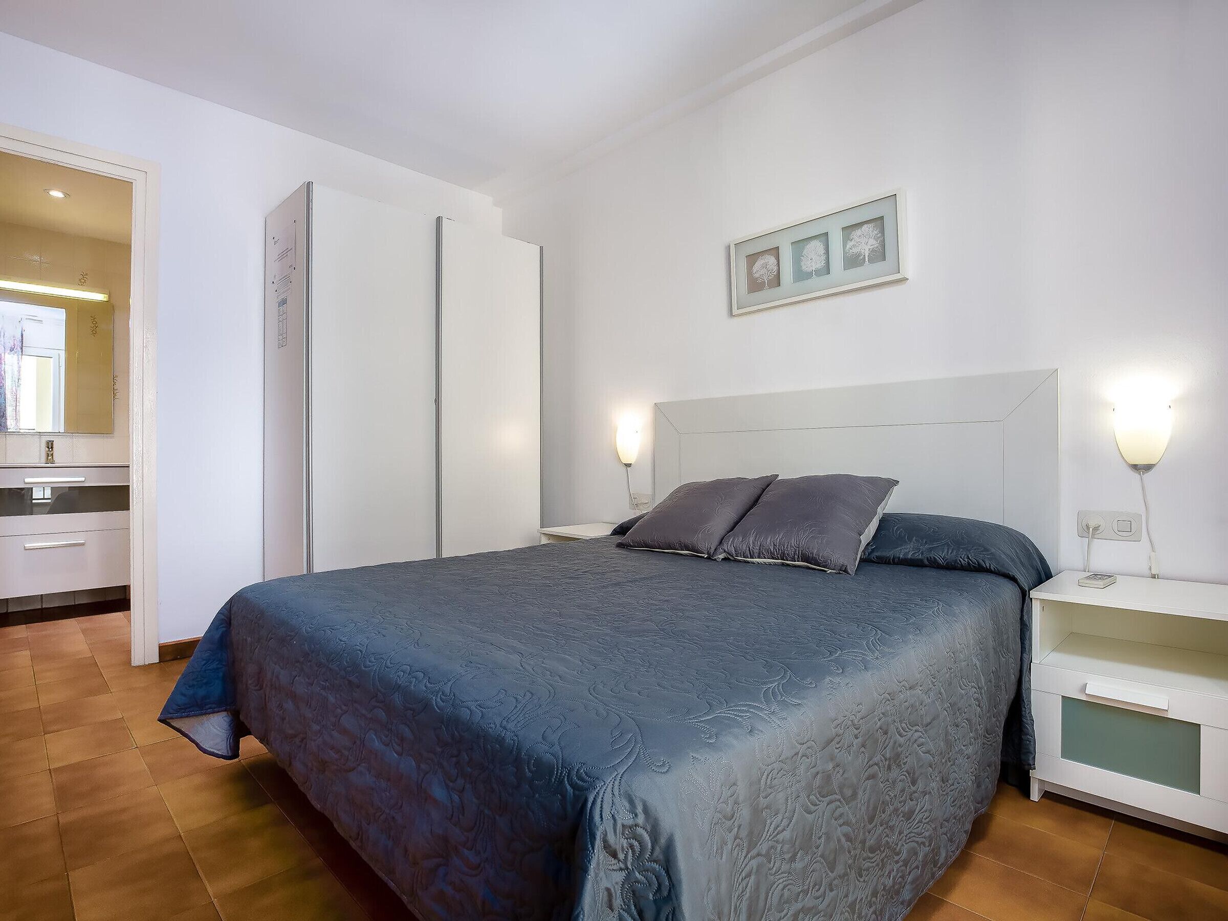 Une chambre à coucher comprenant un lit, des tables de chevet, une armoire et un tableau encadré accroché au mur.