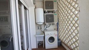 Un área de lavandería con lavadora, dos equipos de aire acondicionado y un calentador de agua.