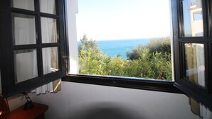Une pièce dotée d’une grande fenêtre donnant sur la mer et la verdure.