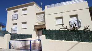 En tvåvåningsbyggnad med en beige fasad, en grind vid ingången och en skylt med texten ”Empuries 7”.