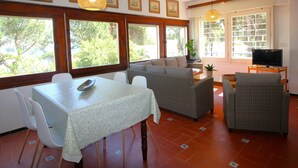 A dining area with a table and chairs, a sofa, and a television. - Spacious Apartment with Large Terrace and Garage in Fané de Baix, 50m from Llançà Bypass (Llançà)