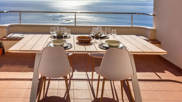 A dining table set for four with a view of the sea.