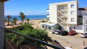 Ein mehrstöckiges Gebäude mit Balkonen, einem Parkplatz und Blick auf Strand und Meer.