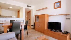 Ein modernes Wohnzimmer mit Fernseher, Holzschrank und Essbereich.