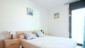 Ein Schlafzimmer mit einem Bett, zwei Nachttischen mit Lampen, einer Holzkommode und zwei gerahmten Bildern an der Wand.