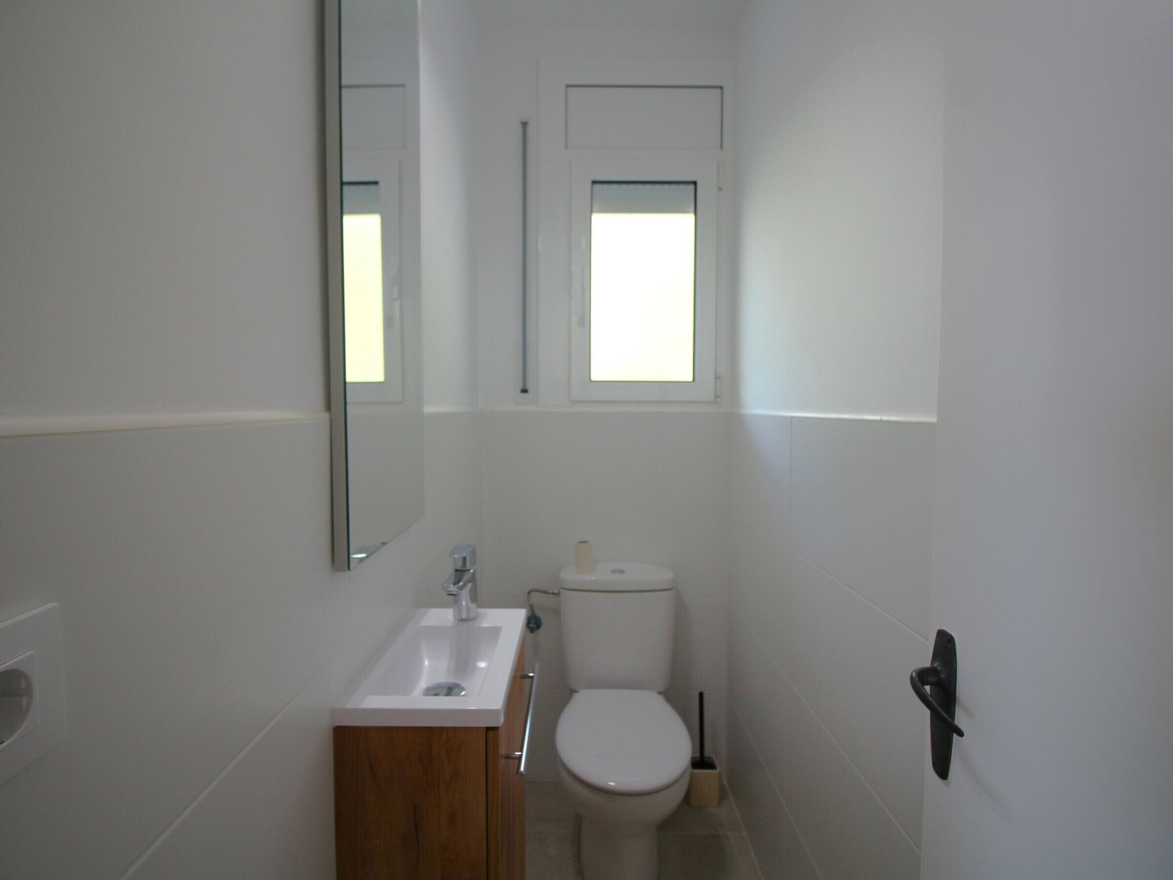 A small, clean bathroom with a white sink, toilet, and a mirror above the sink.