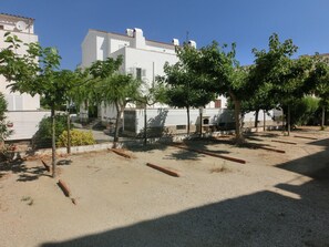 Un quartier résidentiel caractérisé par des bâtiments blancs, des arbres et un sol recouvert de gravier.