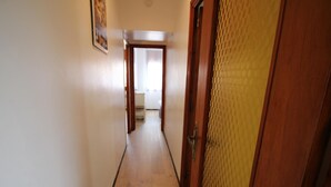 A narrow hallway with wooden flooring and a door on the right. - 2-BR Apartment with Terrace, Sea View & Parking - Sleeps 6 (Llançà)