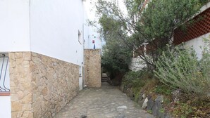 A narrow stone-paved alleyway flanked by white walls and a stone wall, leading to a staircase. - 2-BR Apartment with Terrace, Sea View & Parking - Sleeps 6 (Llançà)
