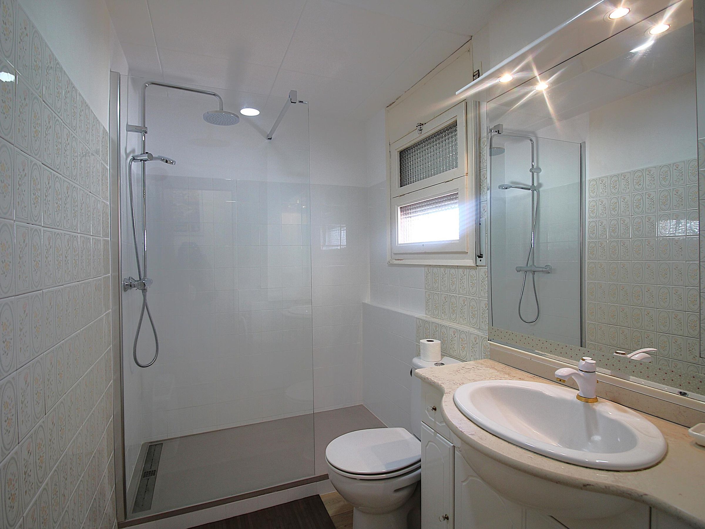 A modern bathroom with a shower, toilet, sink, and a large mirror.