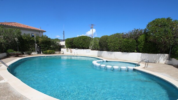 A swimming pool with a tiled deck, a small hot tub, and a white wall with a window. - Bright apartment with pool and terrace, near the beach (Llançà)