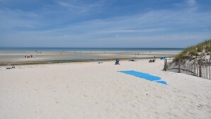 A sandy beach with a wooden fence and a blue tarp on the sand. - Sunroom, Spacious Deck, 8 Mins to Mayflower Beach! (Dennis)