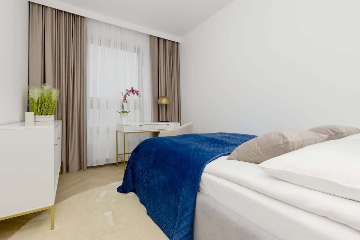 Moderni hotellihuone, jossa on sänky, työpöytä ja tuoli.