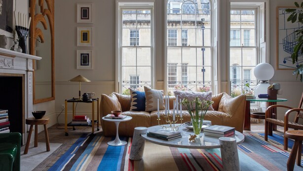 Un salon spacieux avec une grande fenêtre, un canapé en cuir, une table basse et une bibliothèque.