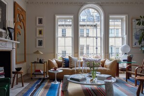 Un salon spacieux avec une grande fenêtre, un canapé en cuir, une table basse et une bibliothèque.