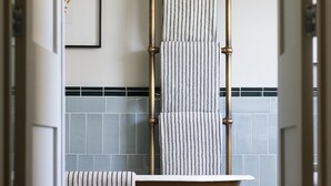 Une salle de bain avec une baignoire sur pieds, une serviette à rayures et un tableau encadré au mur.