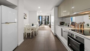 A modern kitchen with white cabinets, a dining area with a table and chairs, and a view of the city through large windows.