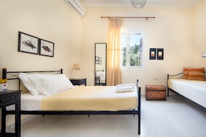 A bedroom with a bed, bedside table, lamp, and a window with curtains.