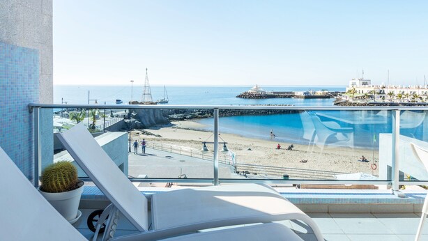 Un balcón con vistas a una playa, un muelle y un faro.