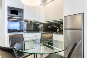 Eine moderne Küche mit einem Glastisch, Edelstahlgeräten und Blick auf die Stadt.