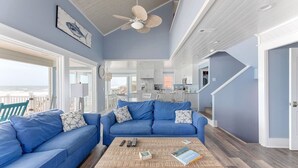 Un vaste espace de vie comprenant un canapé bleu, une table basse en bois et un ventilateur de plafond.