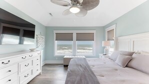 Une chambre à coucher avec un lit, un banc, une commode et un ventilateur de plafond.