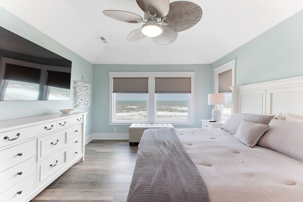 Un dormitorio con cama, una banca, cómoda y ventilador de techo.
