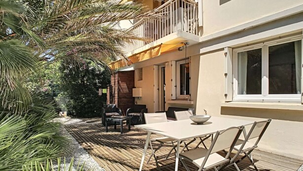 An outdoor patio with a table and chairs, surrounded by a wooden deck and greenery. - Berlioz Garden - Jardin,Free Parking,AC,Wifi (Antibes)