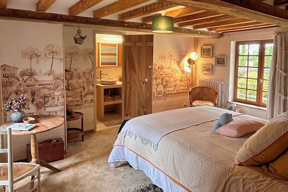 A cozy bedroom with a bed, a chair, a small table, and a wardrobe.