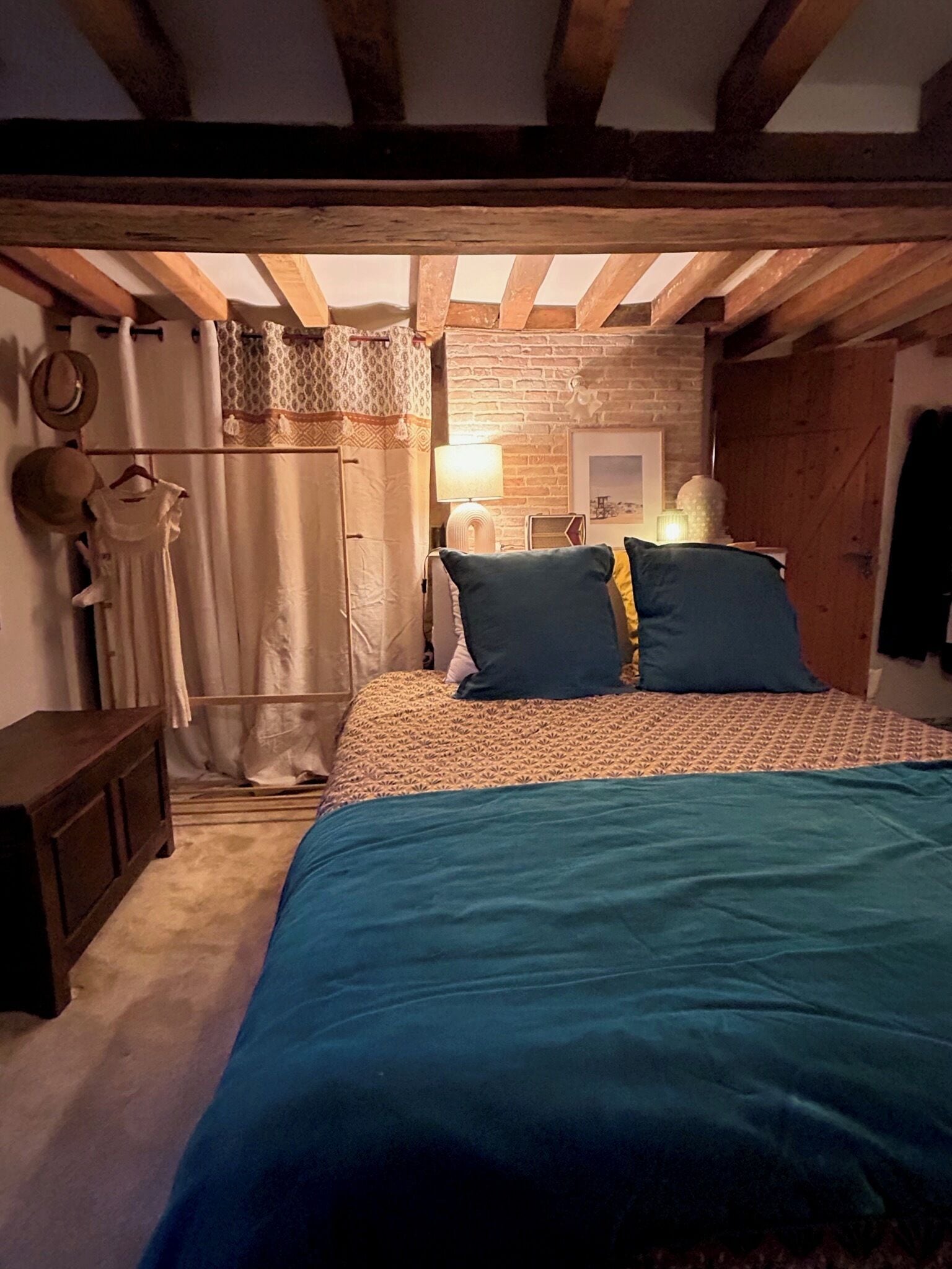 Un dormitorio con una cama, una mesita de noche, una lámpara y una pared de ladrillo.