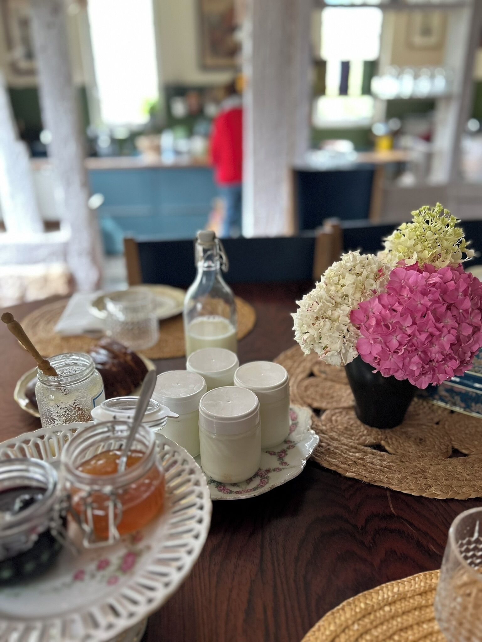 Een tafel met potten honing, potten jam en een vaas met bloemen.