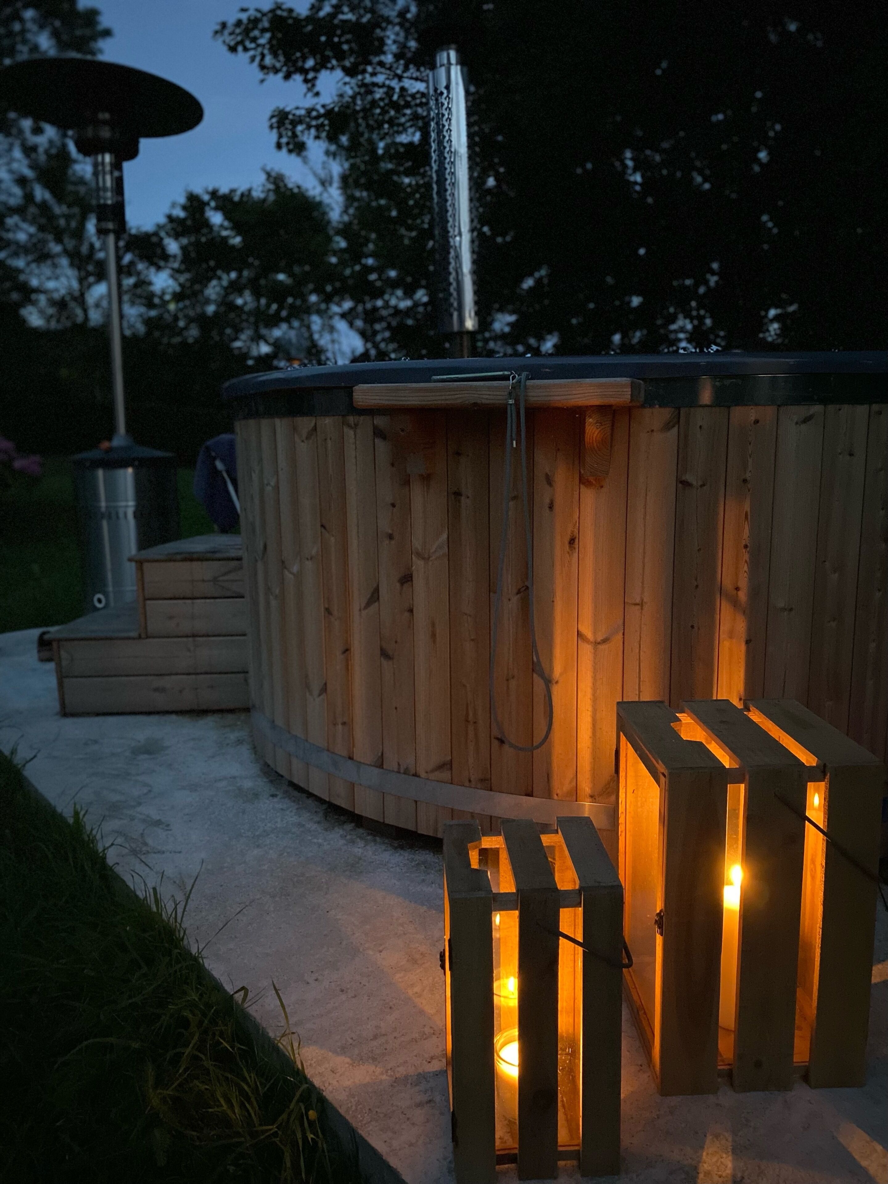 A wooden hot tub with a built-in bench and a small table, surrounded by a concrete deck.