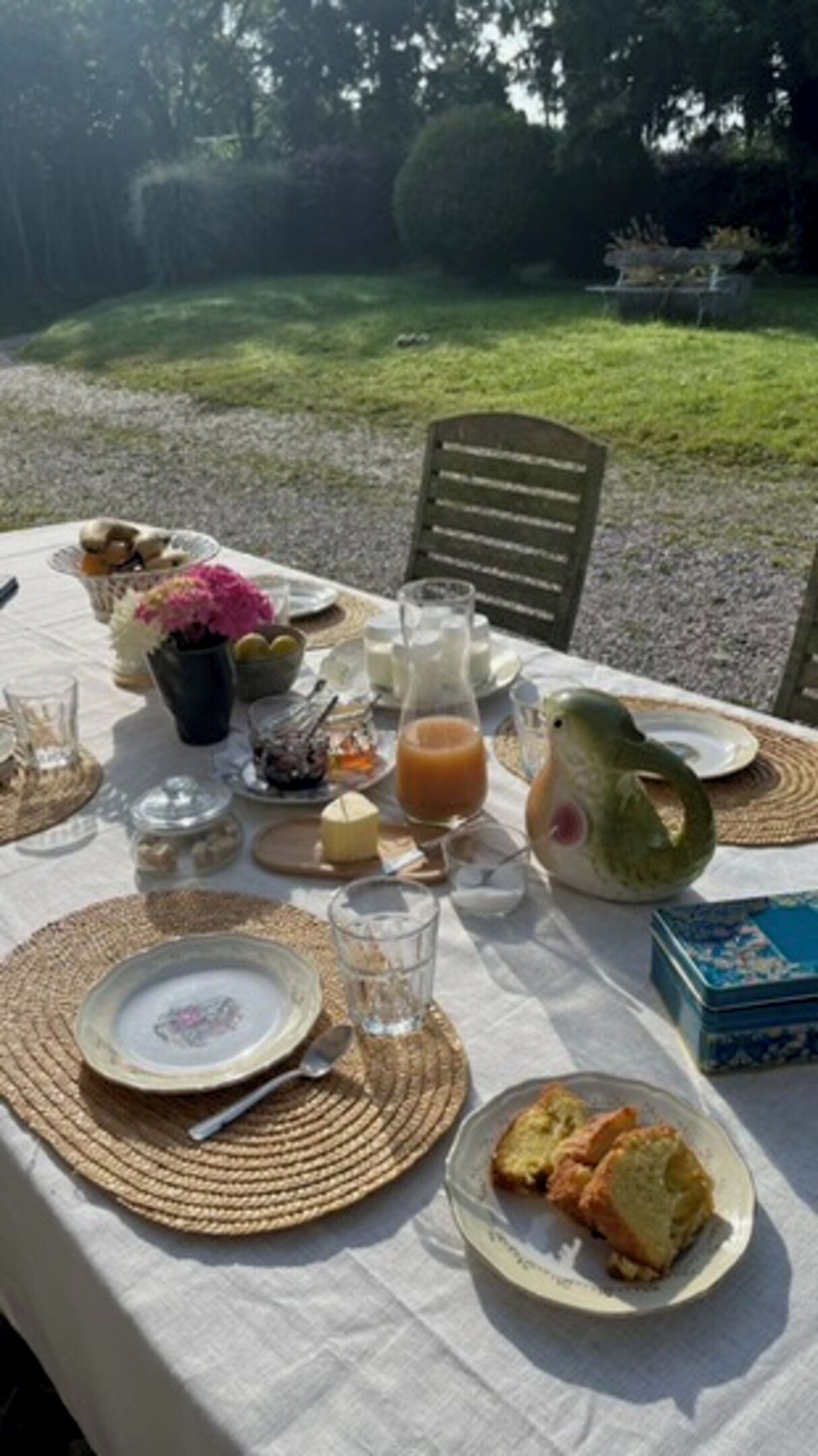 A table set outdoors with plates, glasses, and a pitcher of juice.